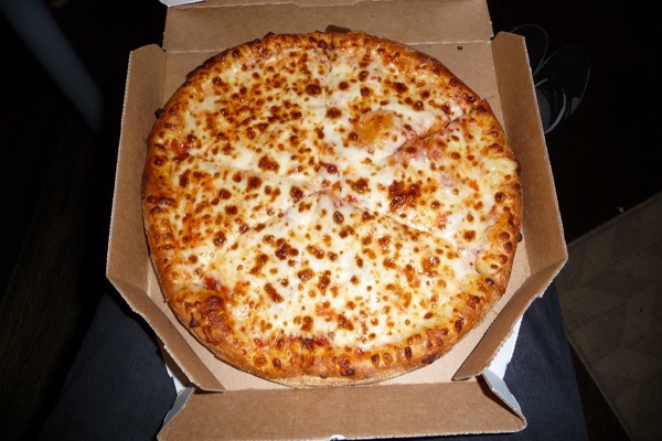 A cheese pizza in its box, photographed on a phone