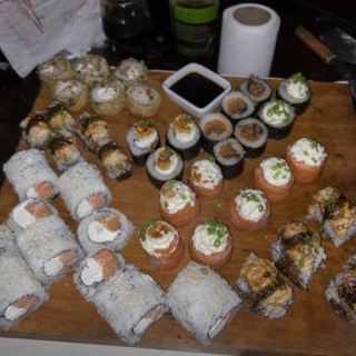 A sushi platter shot on a phone against a busy, uneven background.